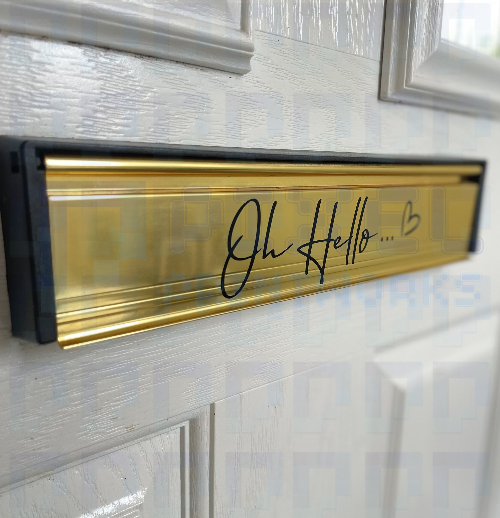 Oh Hello vinyl letterbox sticker in script font applied to a gold mail slot on a white door