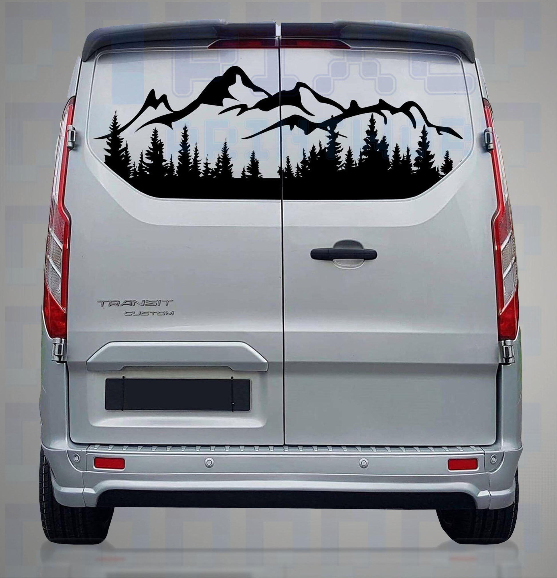 Black vinyl mountain and tree silhouette decal applied to rear window of a silver camper van