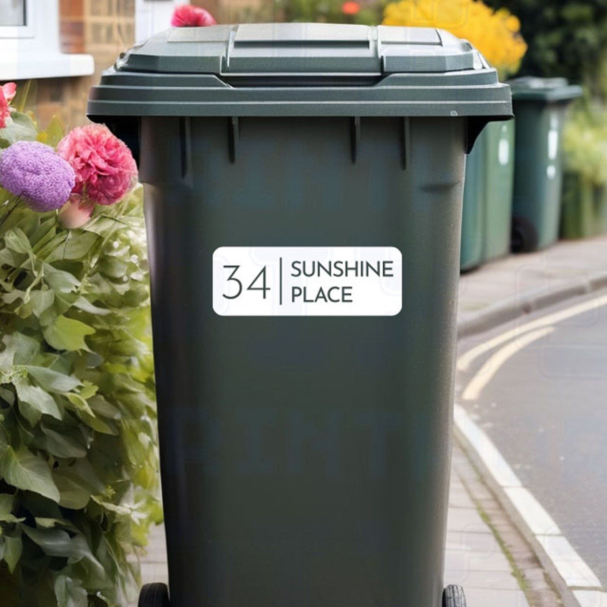 Personalised inverted classic wheelie bin sticker showing bold number and street name inside an outlined box on a bin outside a UK home by Pixel Printworks